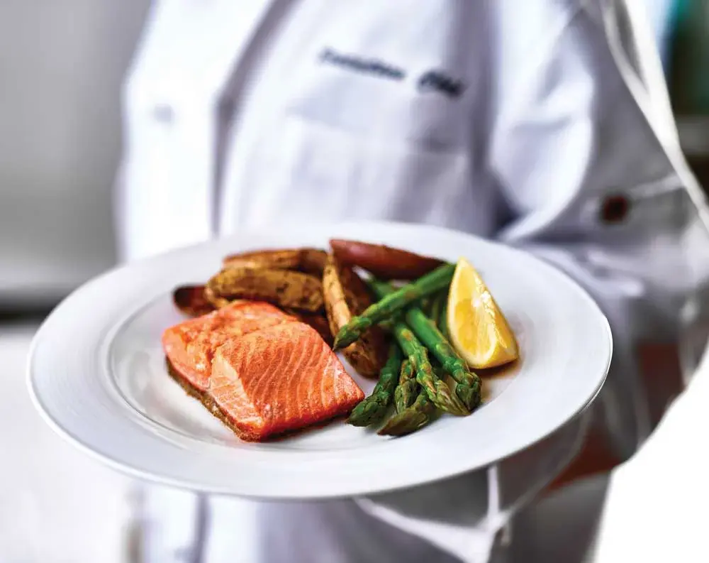 Colonial Gardens Chef Created Meals, chef delivering a finished dish.