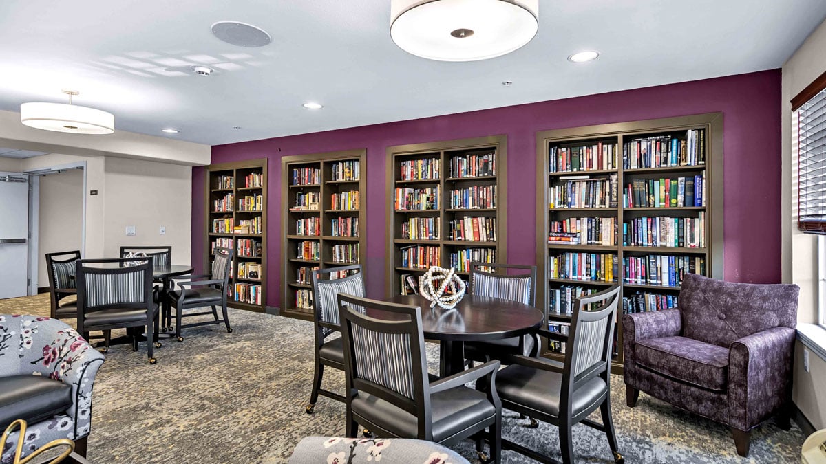 The library at Colonial Gardens with shelves of books and comfortable seating