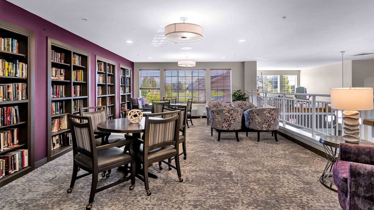 The library at Colonial Gardens with shelves of books and comfortable seating